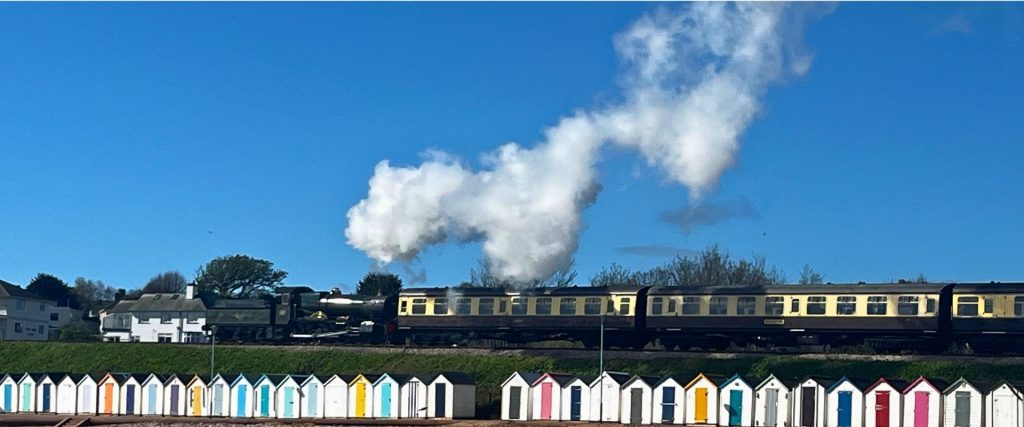 Dartmouth steam train passing behind beach huts in Devon